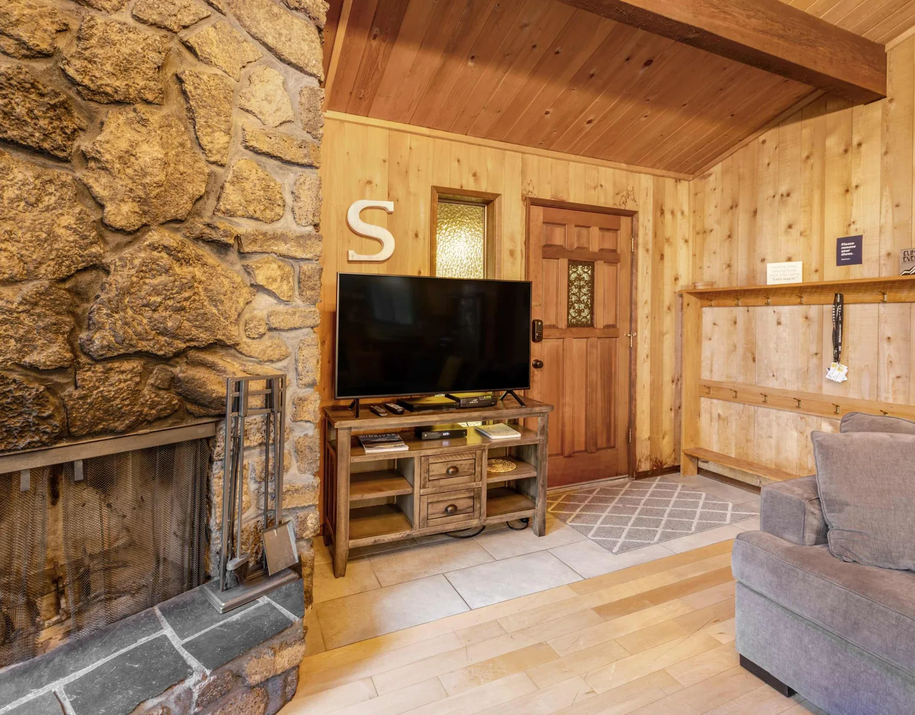 A wood-paneled living room with a stone fireplace and television.