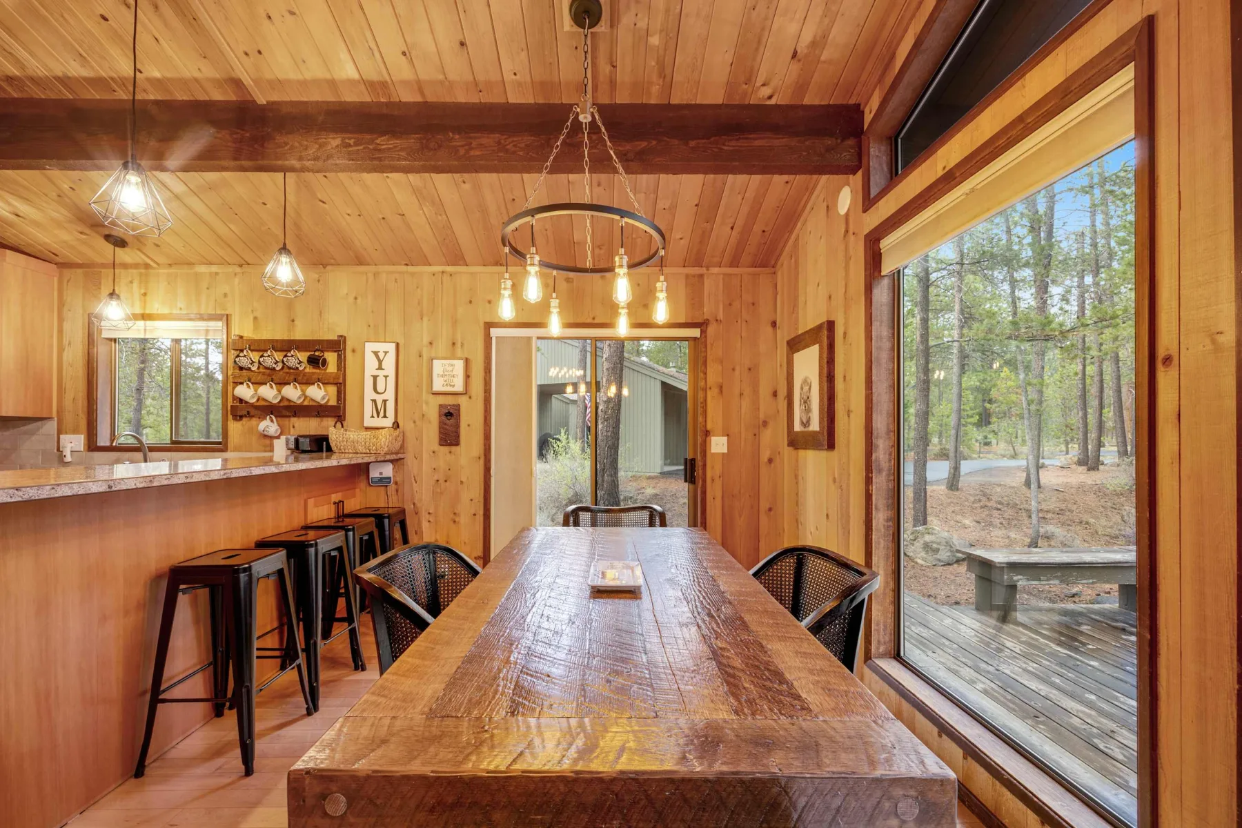 A wood-paneled dining area with a long table beside large windows.