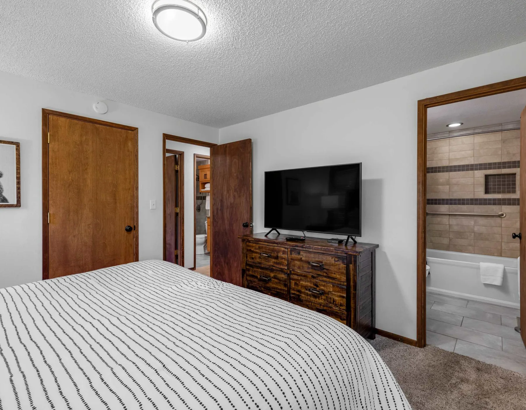 A bedroom with a bed, television, and open doorway to a bathroom.