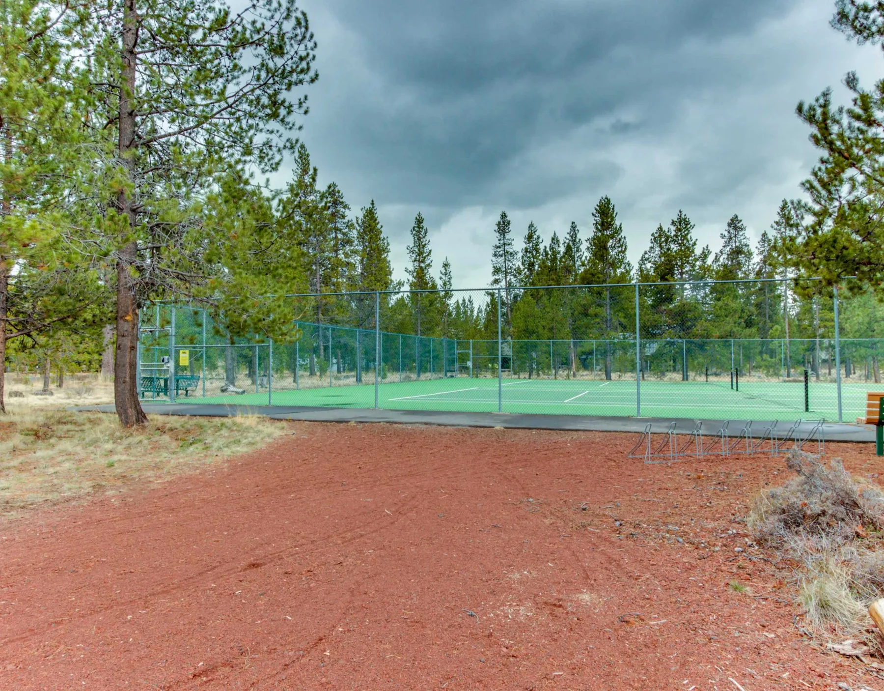 Shared amenity: Outdoor tennis courts sit among pine trees beneath a cloudy sky.