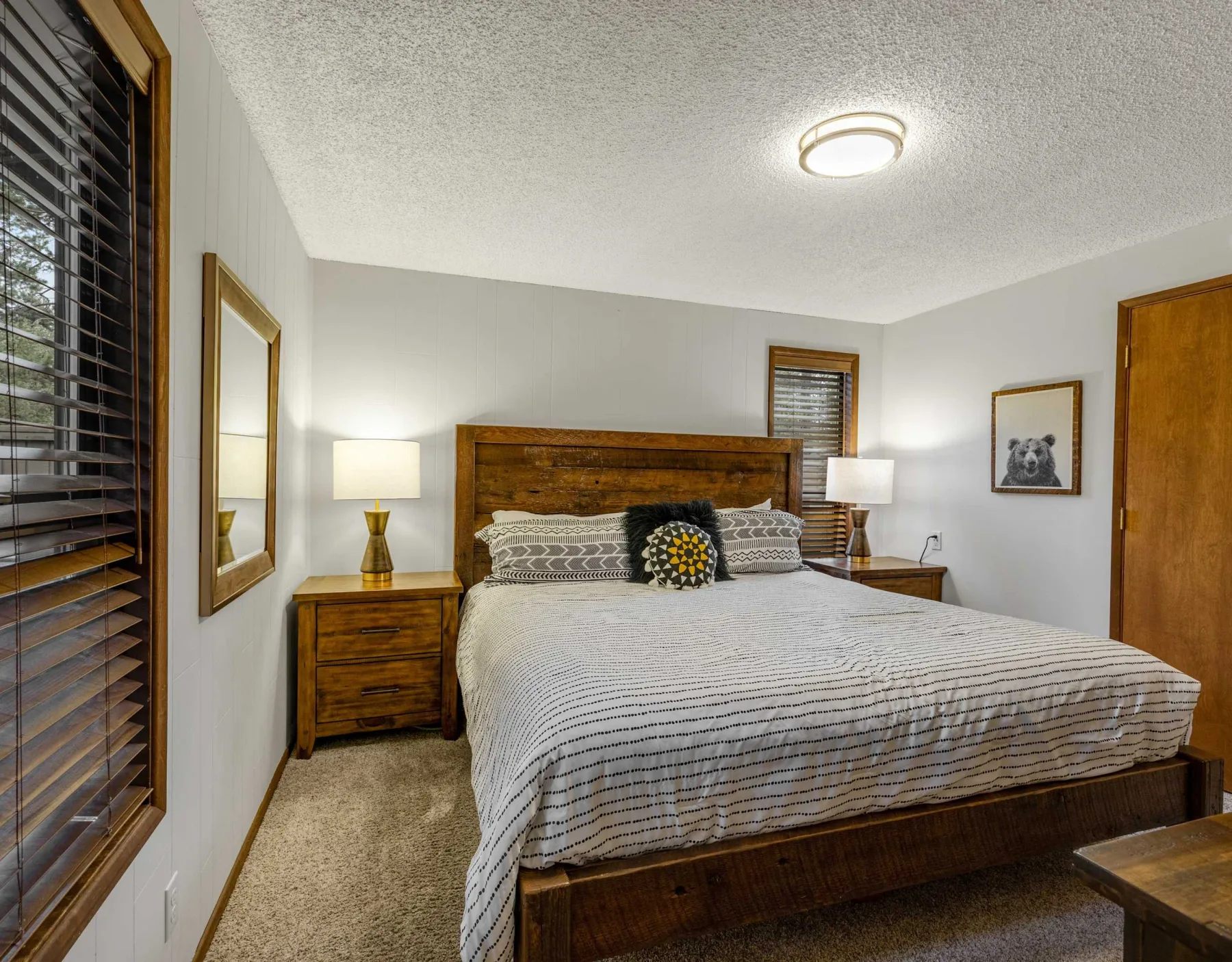 A bedroom with a large bed, wooden headboard, and bedside tables.