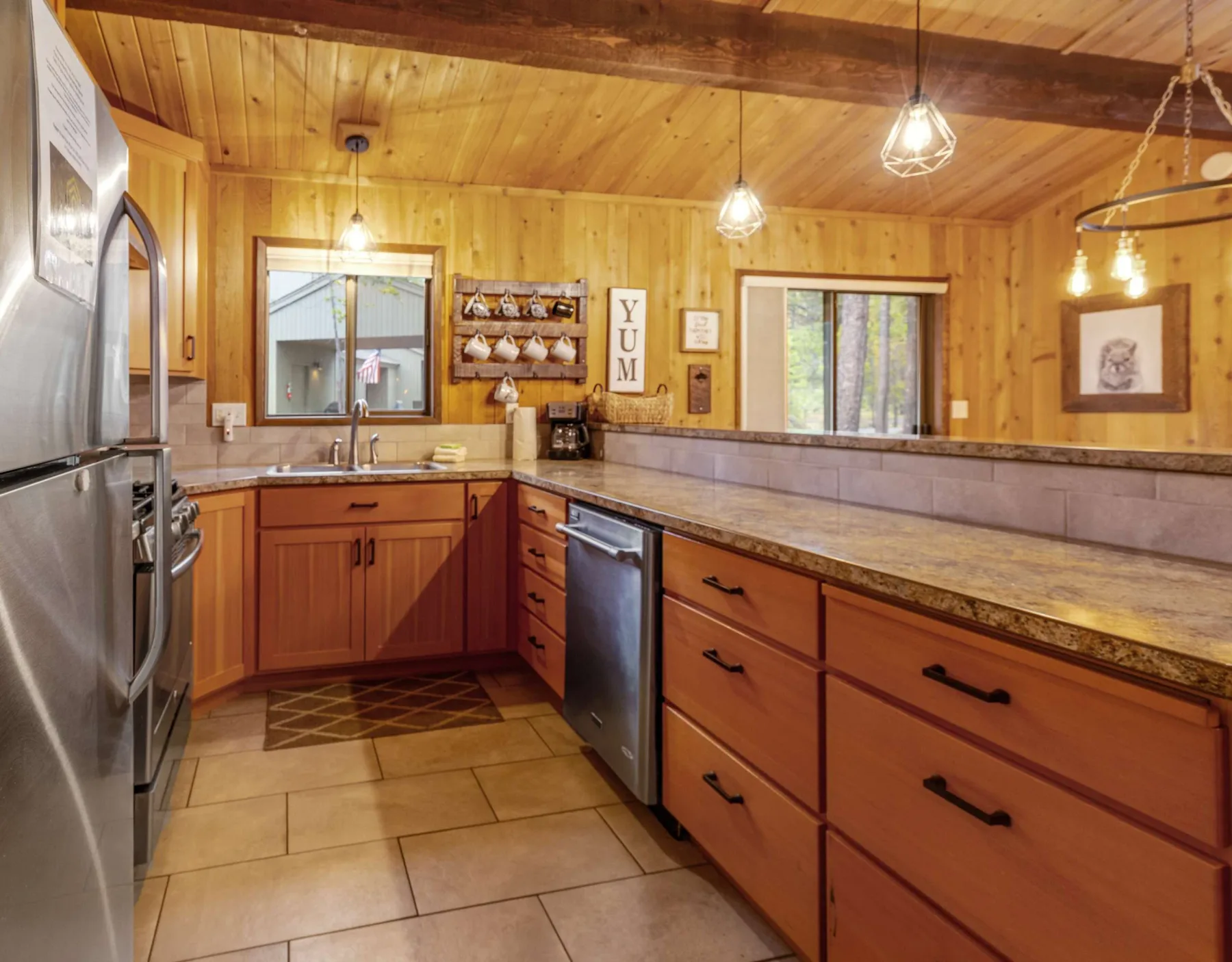 A wood-paneled kitchen with a long counter, cabinets, and stainless steel appliances.