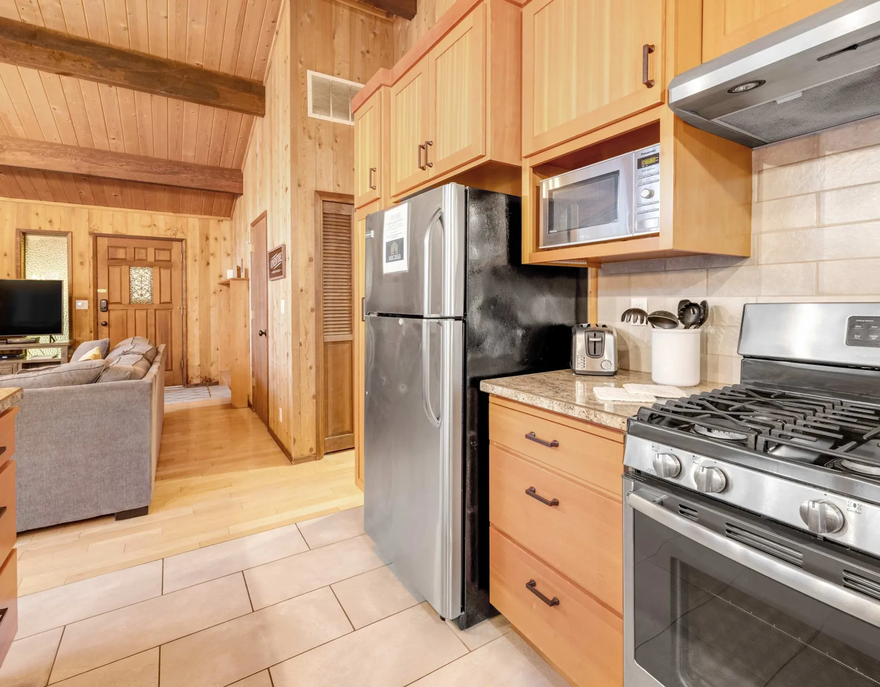 A wood-paneled kitchen with a refrigerator, microwave, and stove.