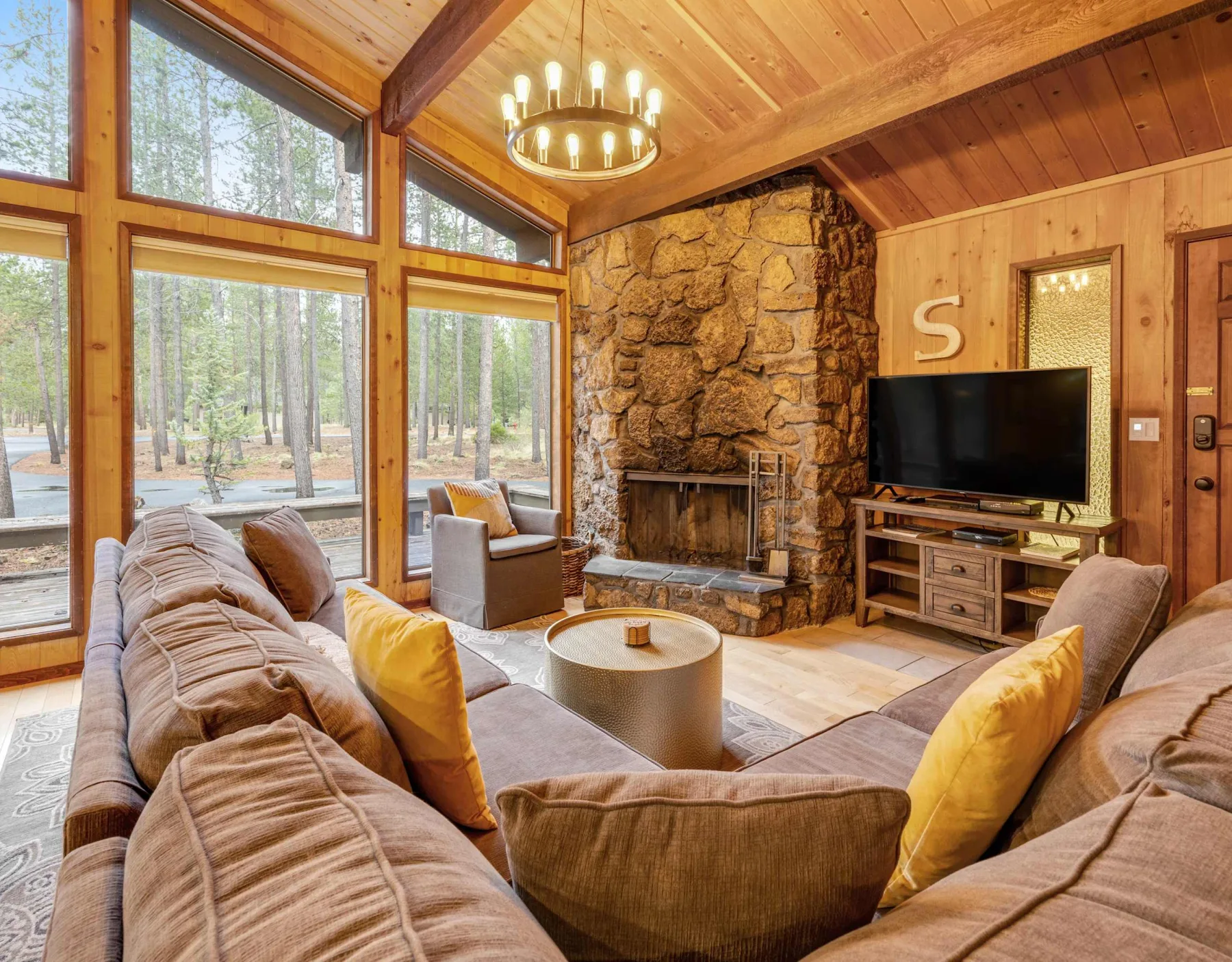 A wood-paneled living room with seating arranged around a stone fireplace.