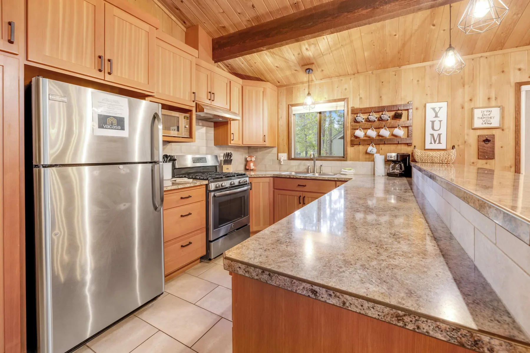 A wood-paneled kitchen with stainless steel appliances and a long central island.