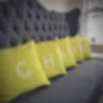 Representative hotel space: A row of yellow cushions rests against a tufted dark wall in a lounge area.
