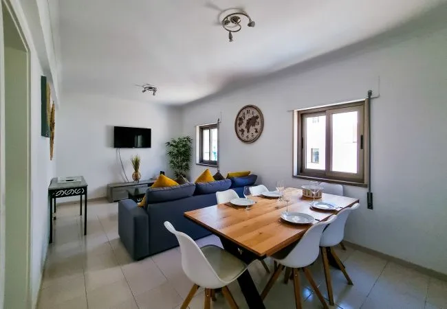 A living and dining area with a blue seating area and a wooden dining table.