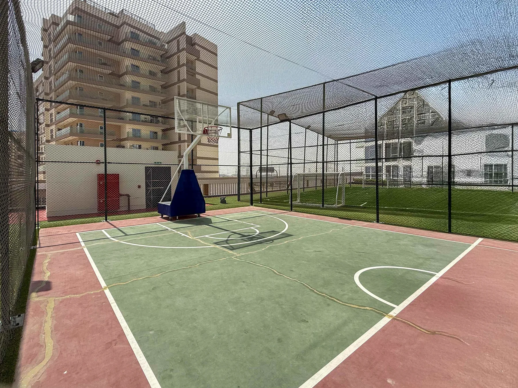 Zona común: Una cancha de baloncesto al aire libre está junto a un campo cercado.