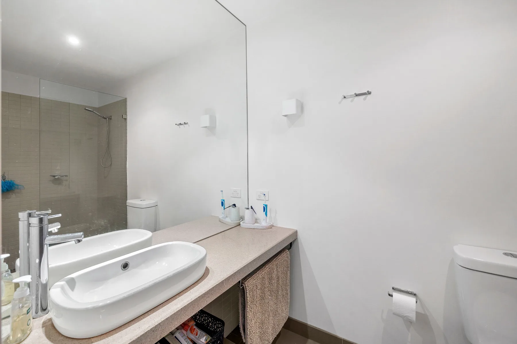 Un lavabo de baño se encuentra junto a una zona de ducha con azulejos.