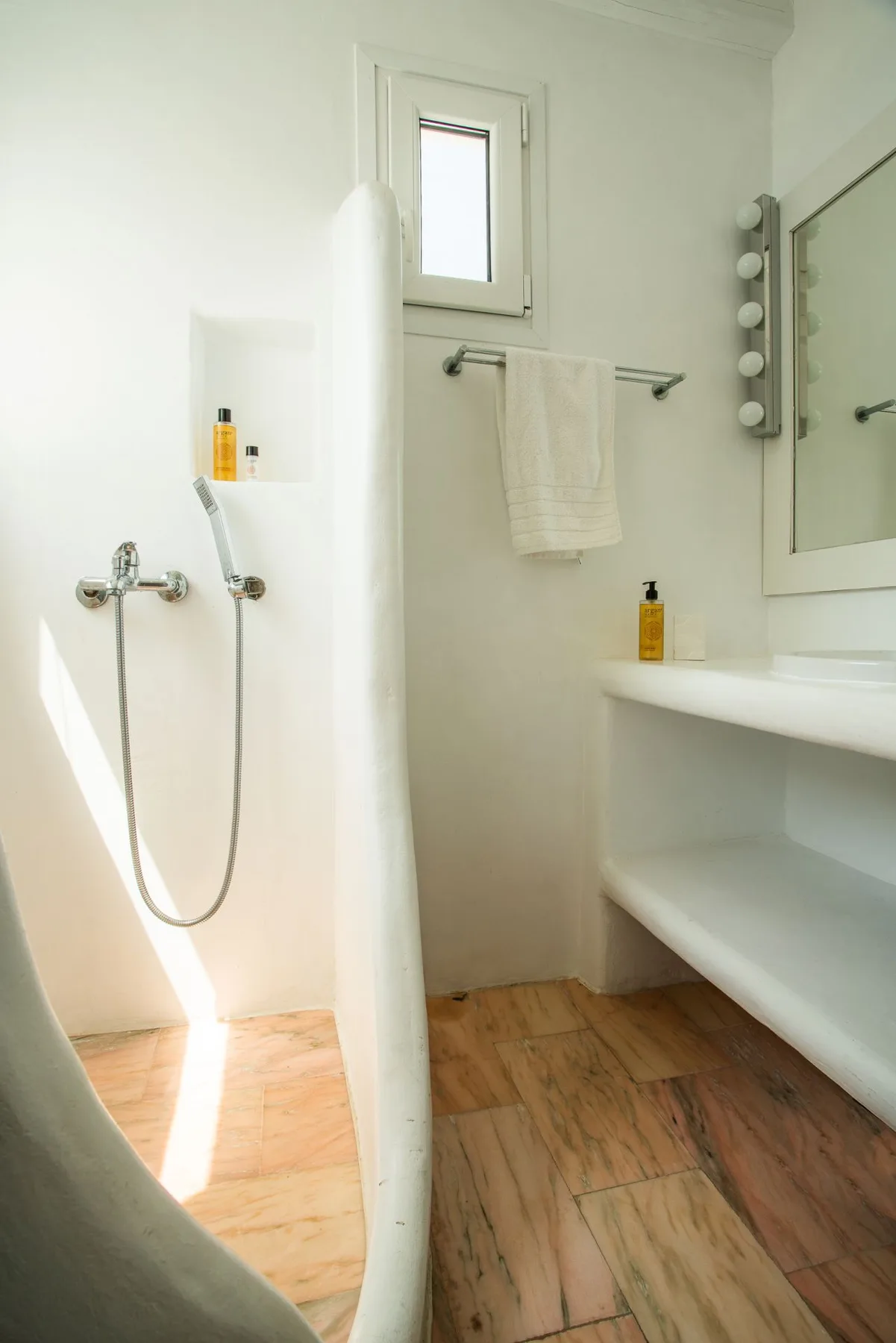 A bright bathroom with a shower, towel rail, and white vanity.