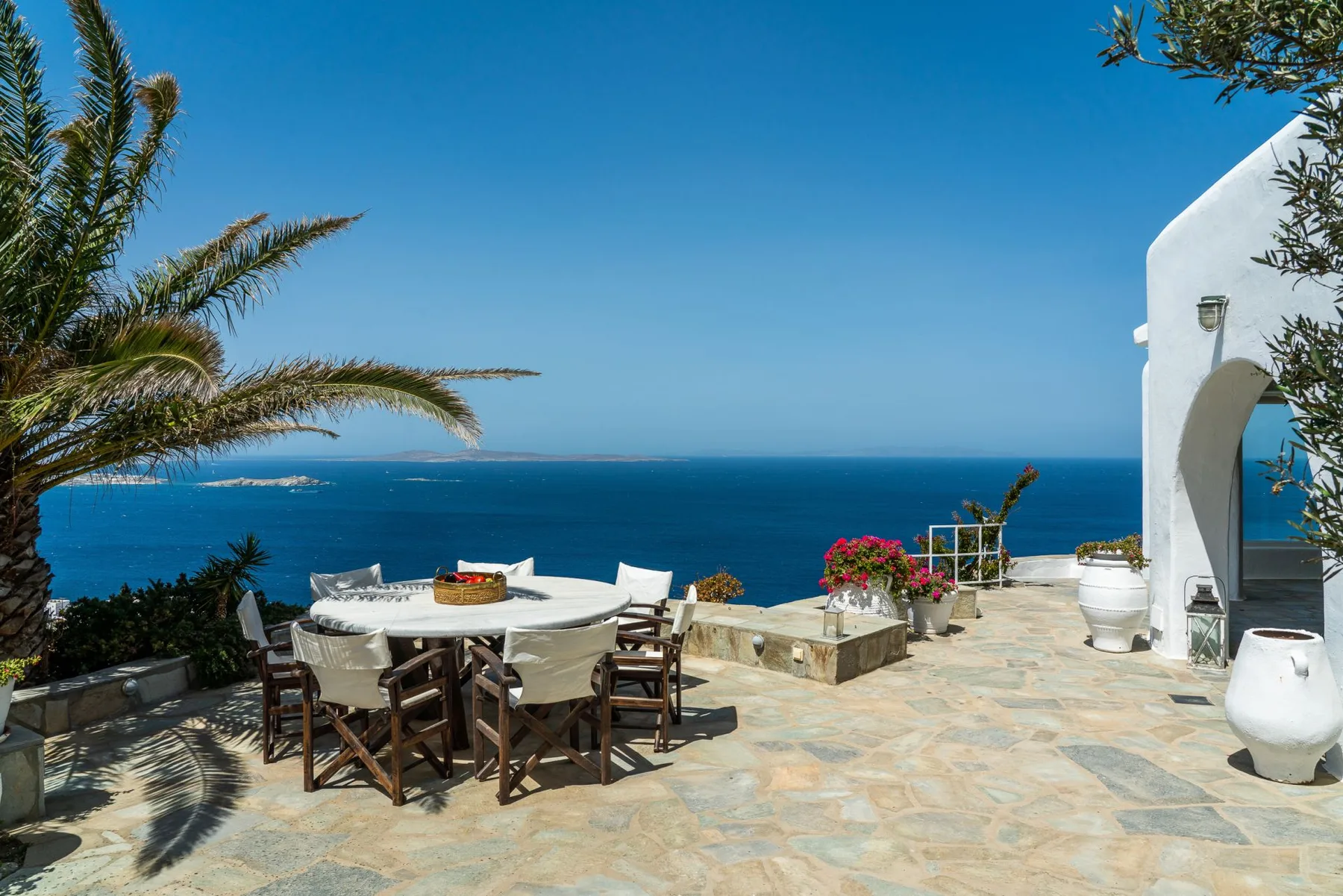 A seaside terrace with an outdoor dining table overlooking the blue sea.