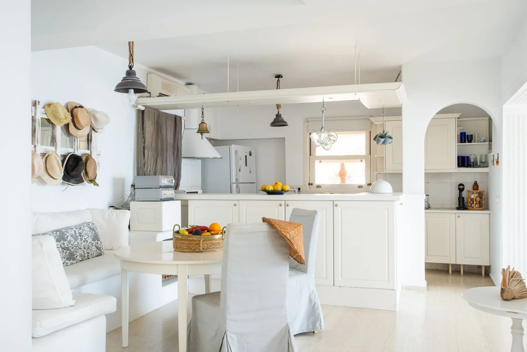 A bright open-plan kitchen and dining area with white cabinetry and a dining table.