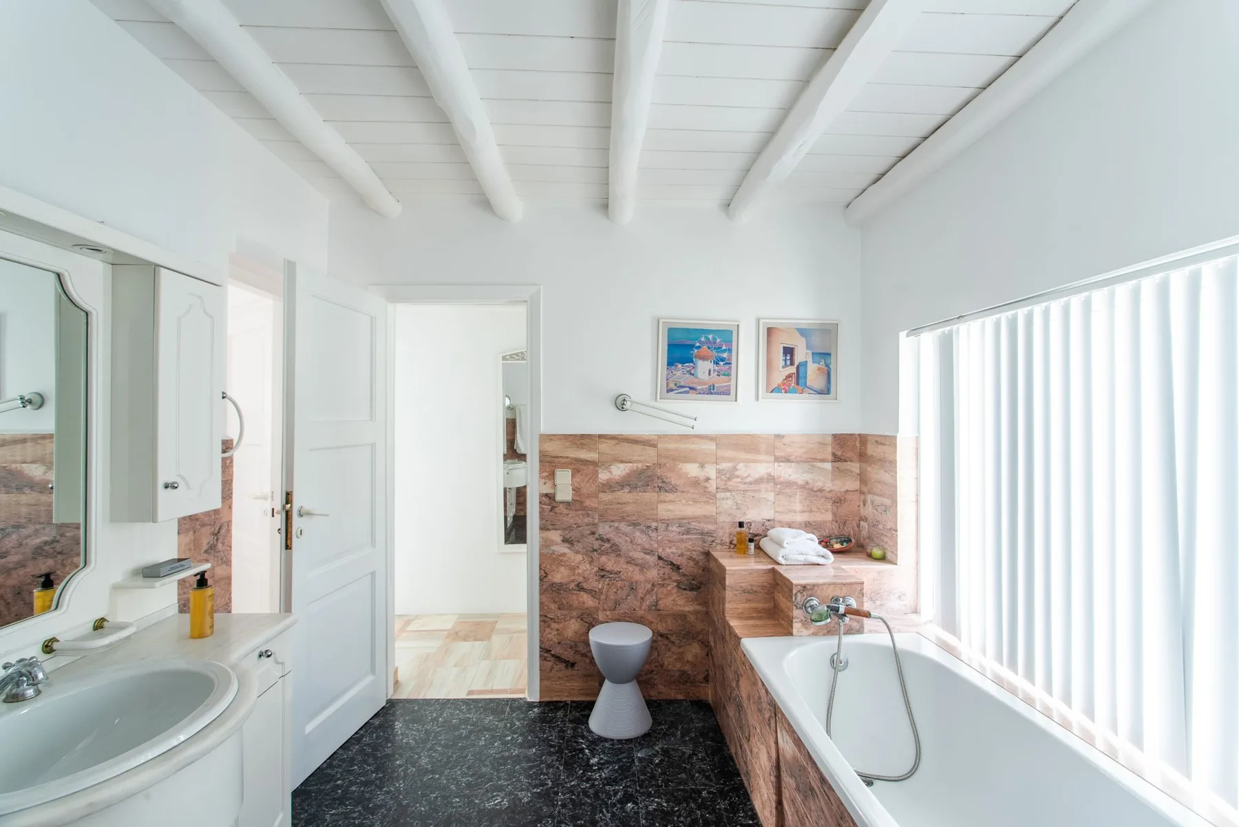 A bright bathroom with a bathtub beside a large window.