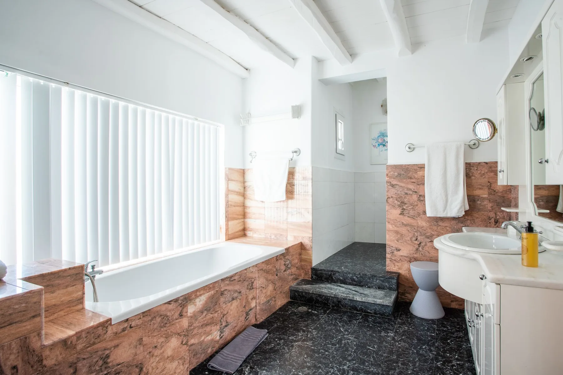 A bright bathroom with a bathtub, shower, and sink.