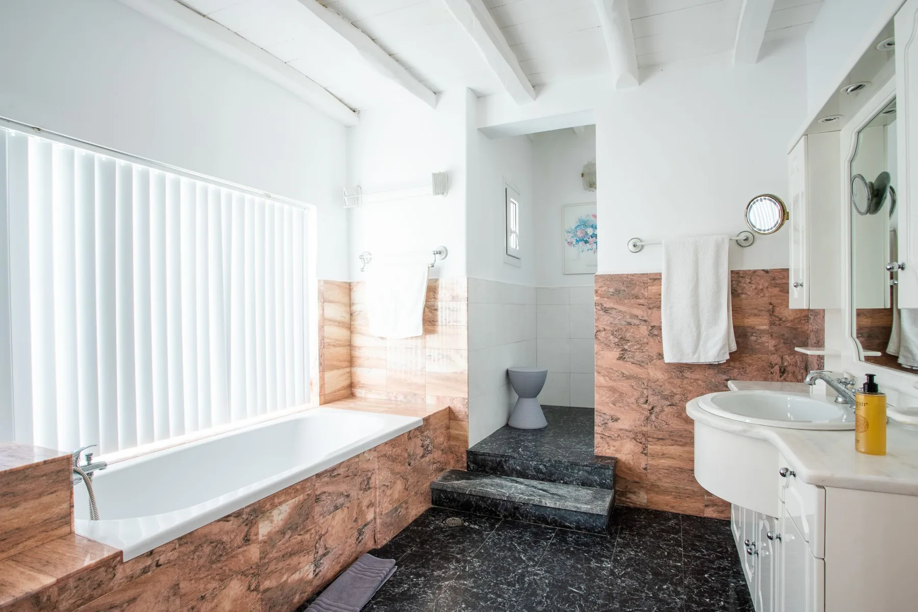 A bright bathroom with a bathtub, shower, and sink.