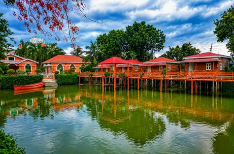 Espacio representativo del hotel: Edificios de tejados rojos y una pasarela de madera bordean un estanque.