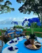 Representative hotel space: An outdoor dining table overlooks a garden and distant water.