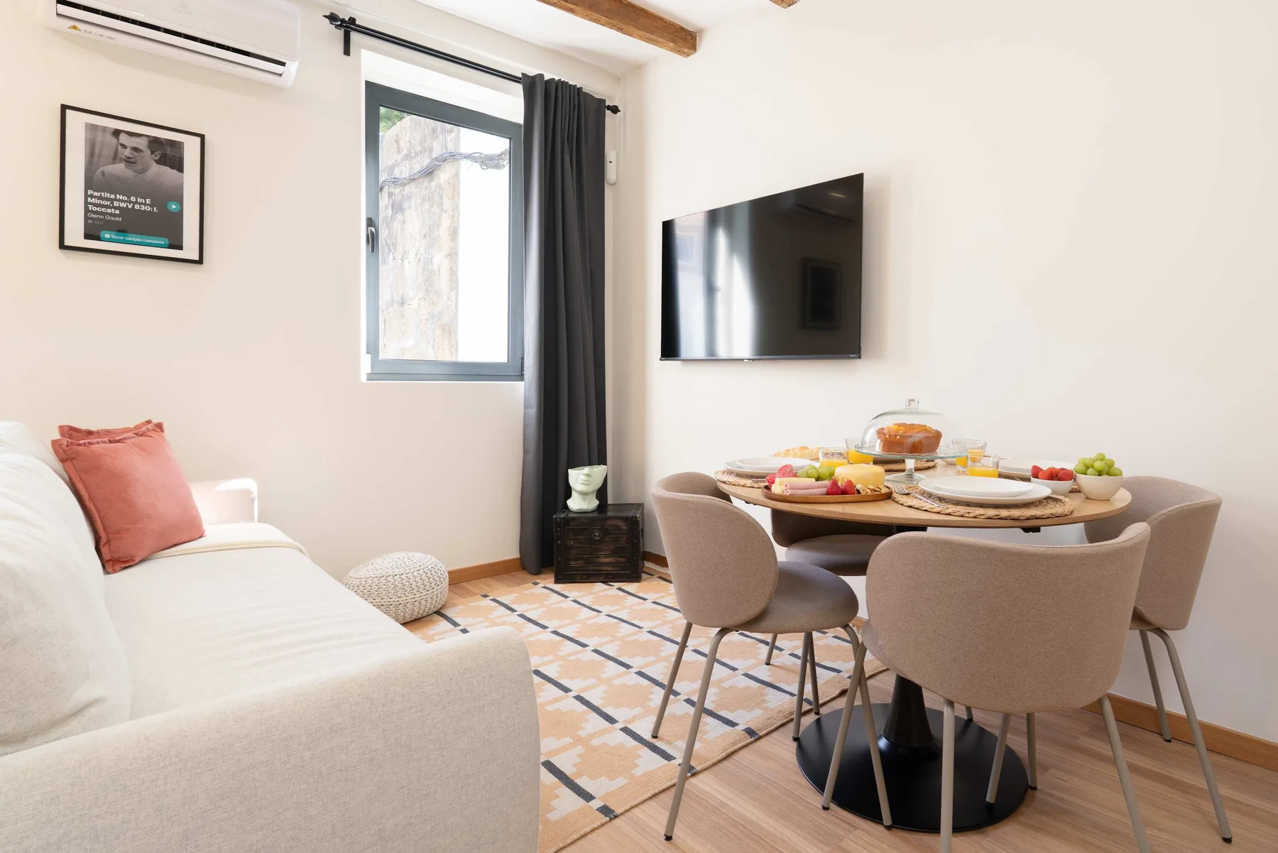 Un comedor con una mesa redonda y asientos tapizados junto a una sala de estar.