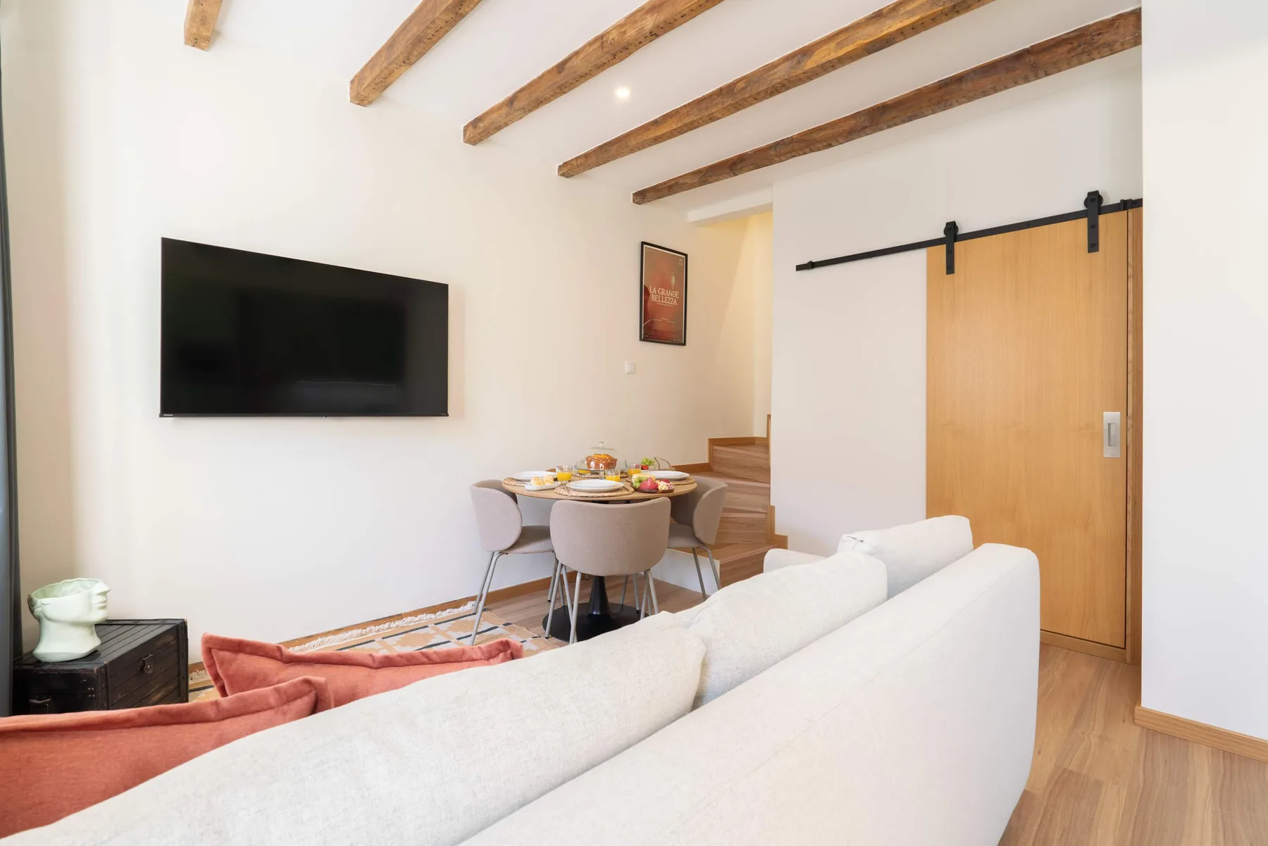 Una sala de estar y comedor con sofá, mesa de comedor y televisor en la pared.