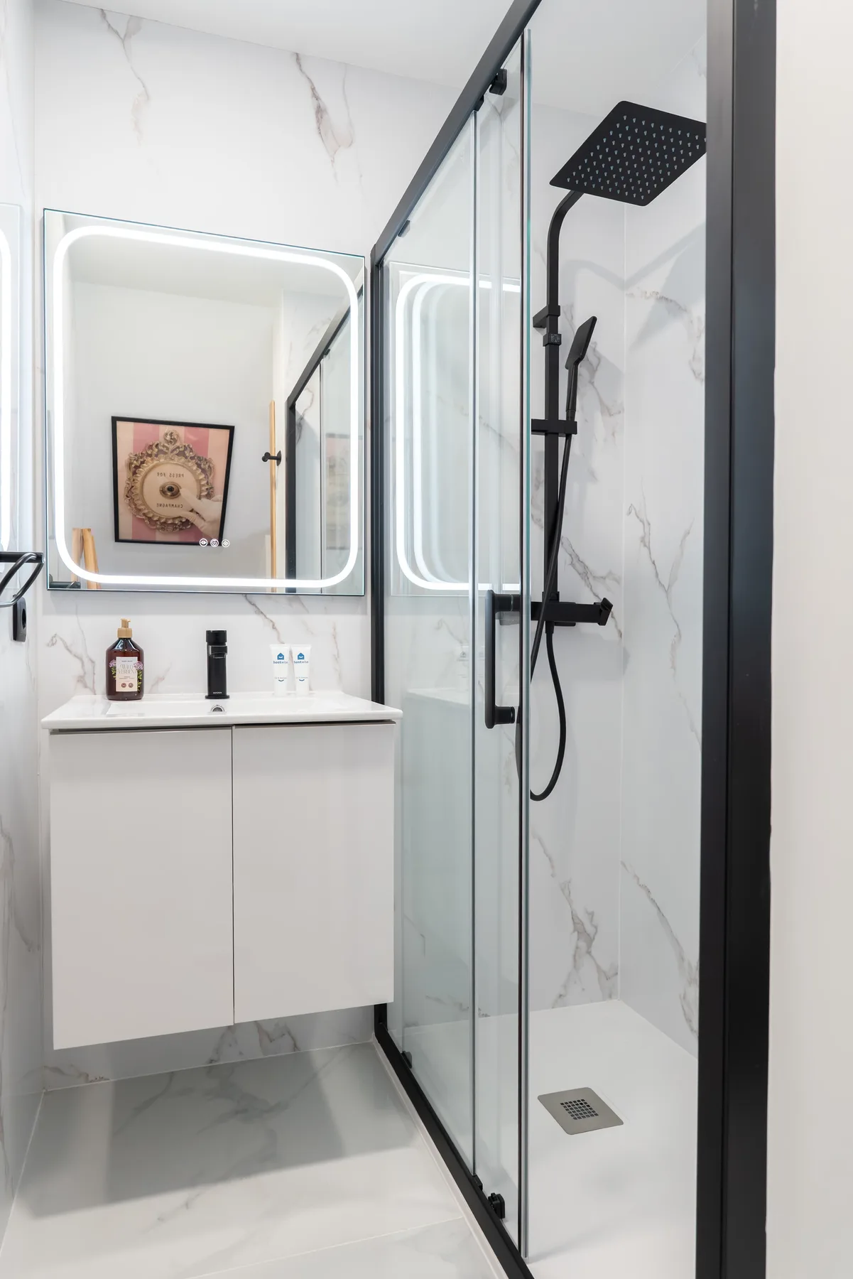 Un baño moderno con ducha de vidrio y espejo iluminado.