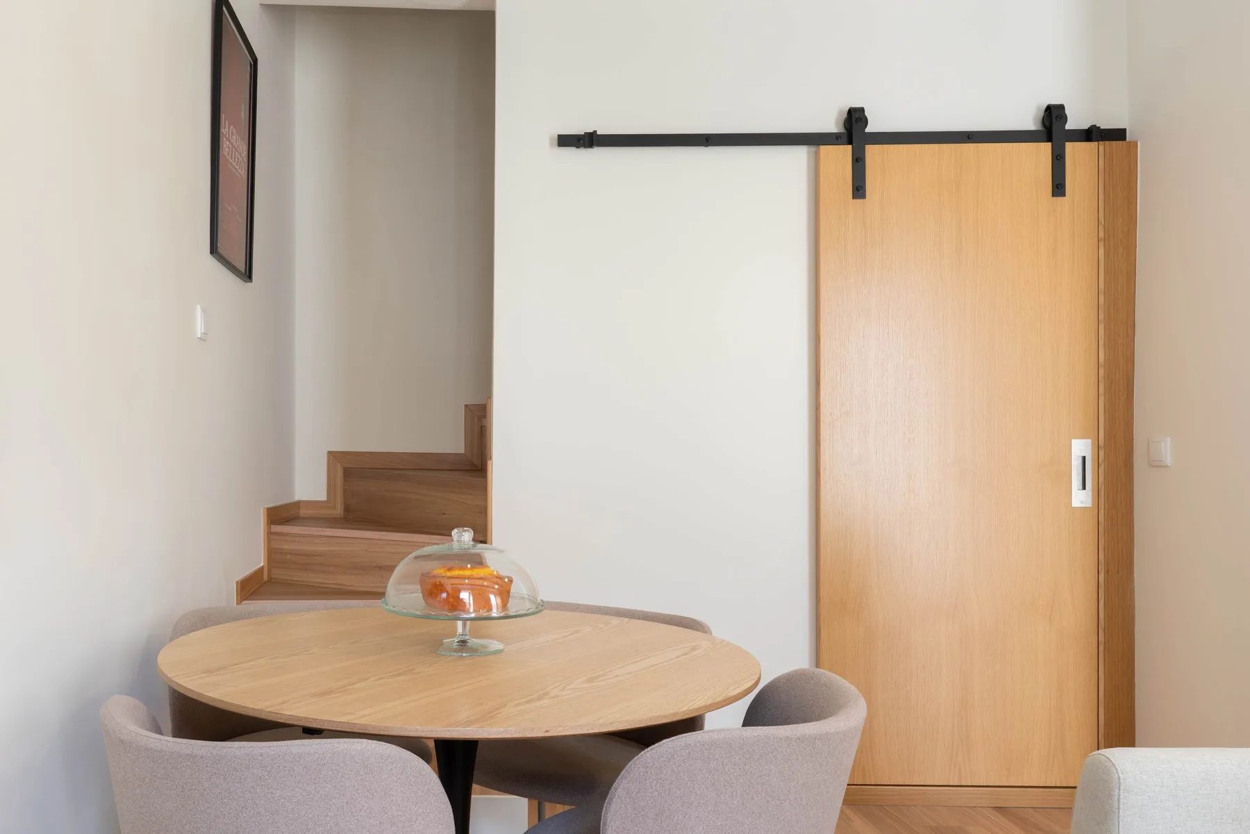 Un comedor con una mesa redonda de madera junto a una puerta corrediza de madera.