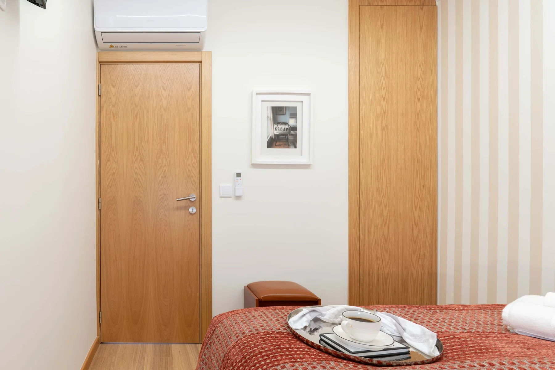 Un dormitorio con una colcha estampada, toallas dobladas y puertas de madera.