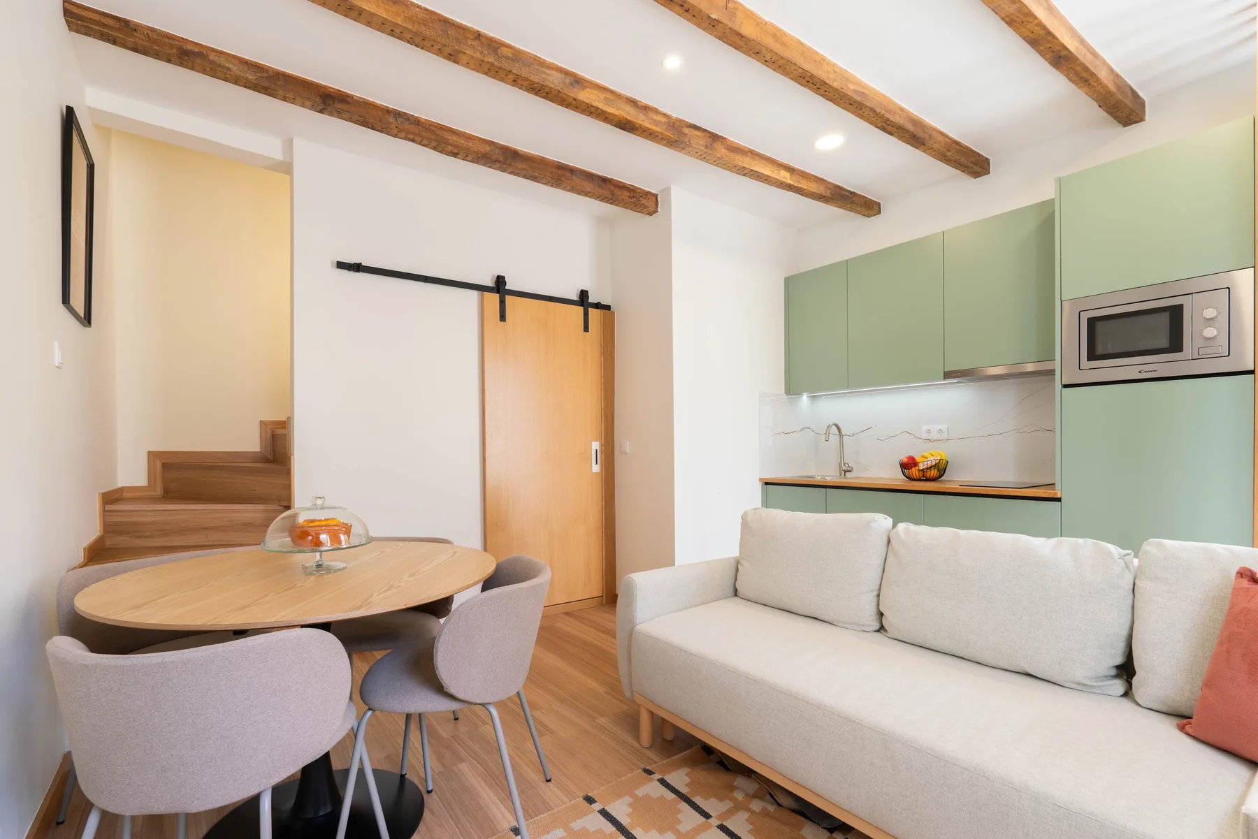 Una luminosa sala de estar con mesa de comedor, asientos y una cocina compacta.