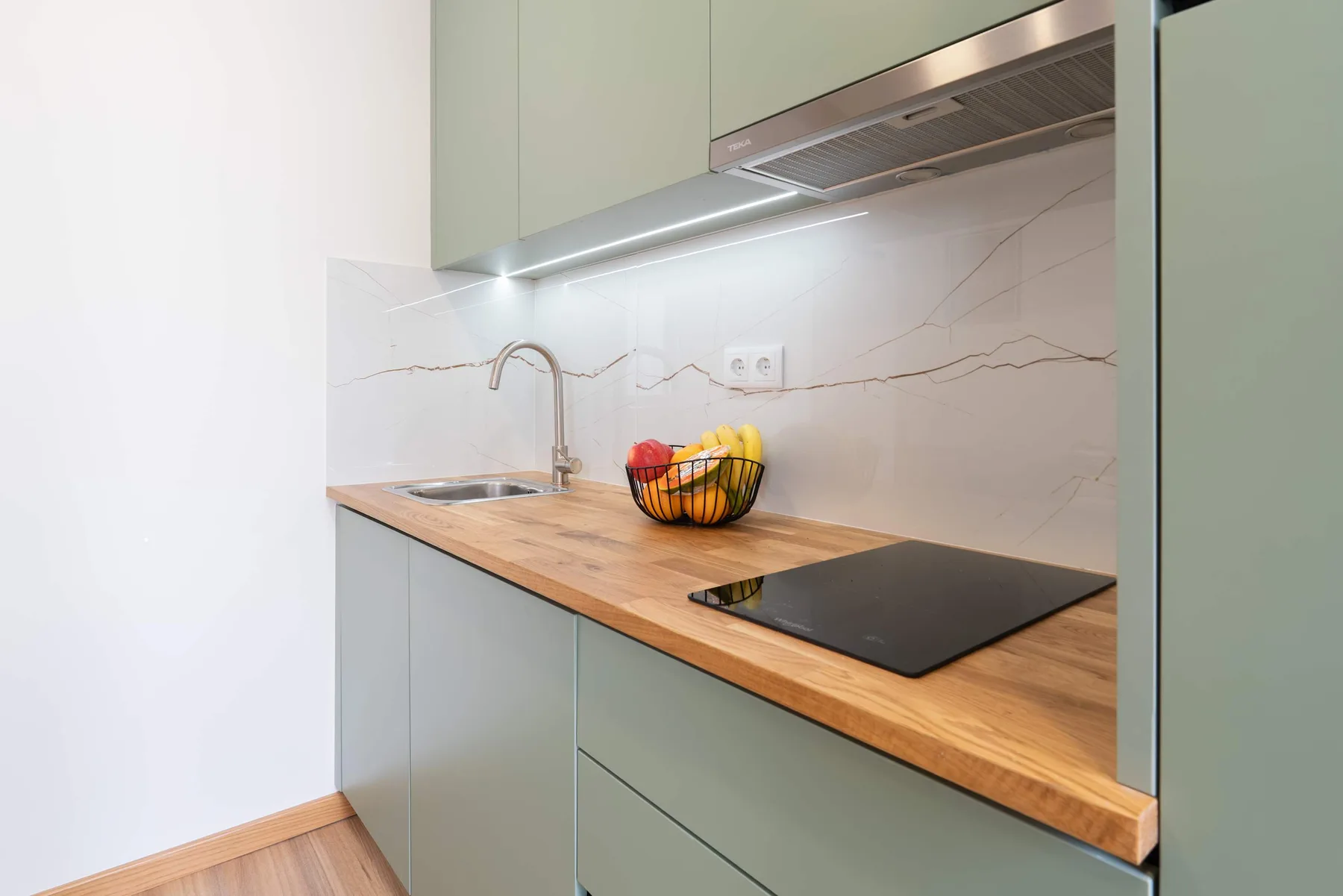 Una cocina moderna con encimera de madera, fregadero y placa de cocción.