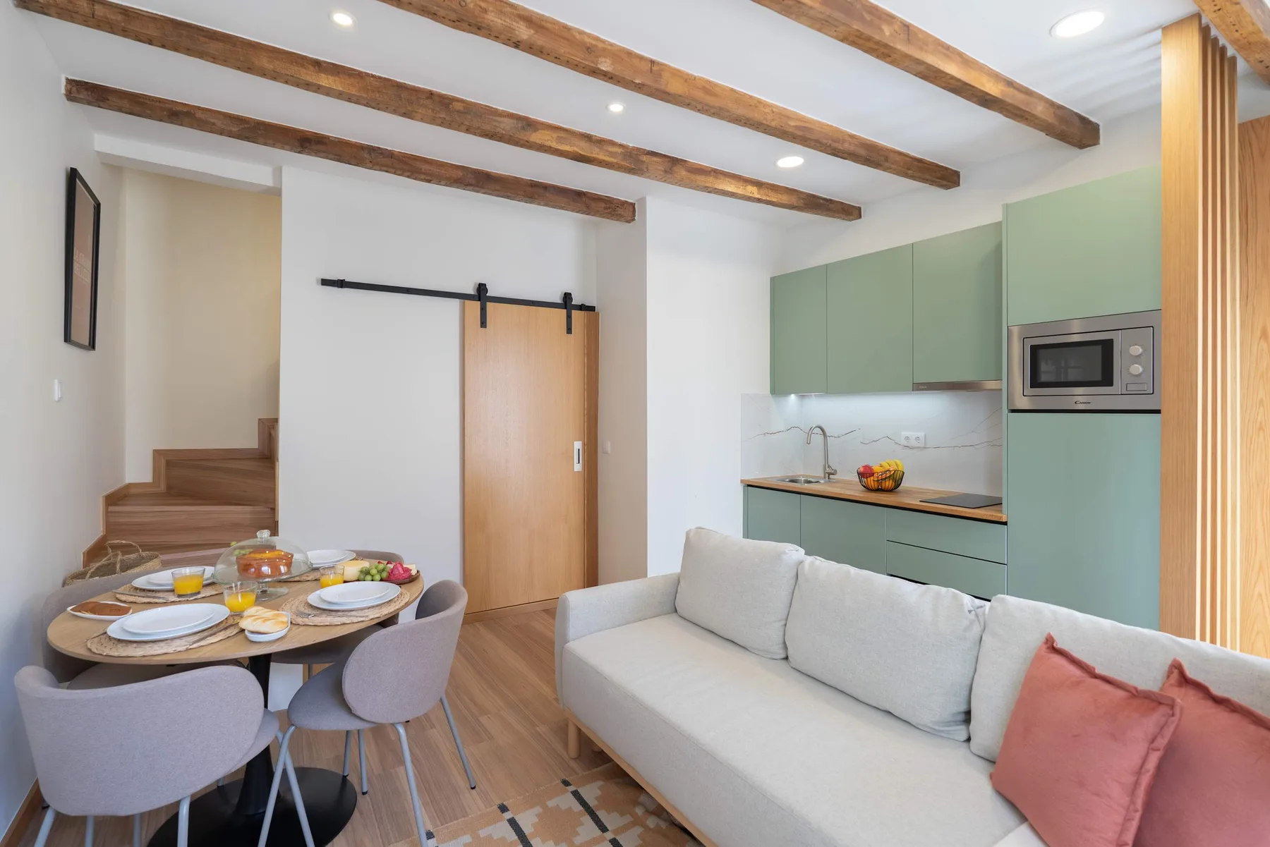 Sala-comedor diáfana con sofá, mesa de comedor y cocina compacta.