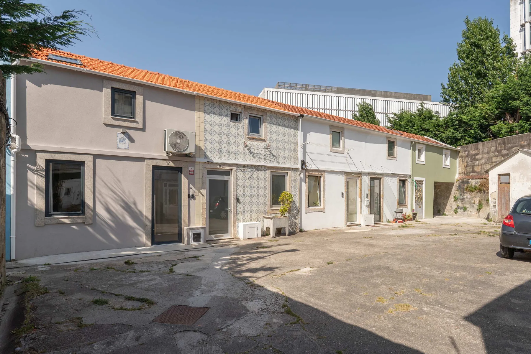 Zona común: Una hilera de edificios bajos bordea un patio pavimentado y soleado.