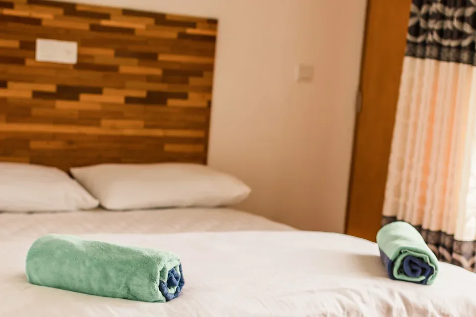 Espacio representativo del hotel: Un dormitorio con una cama y toallas dobladas sobre la ropa de cama.