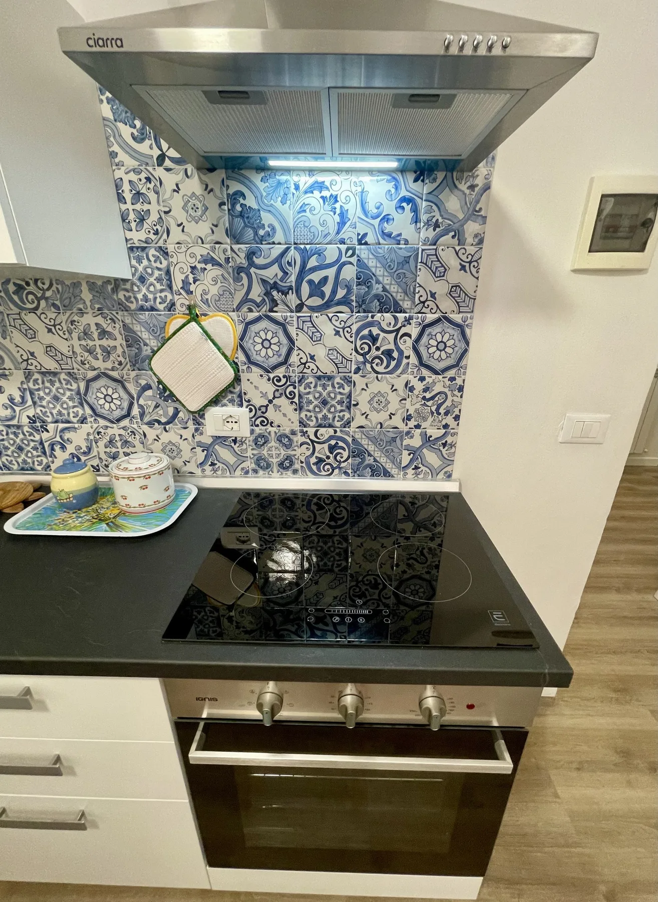 A kitchen cooking area with a black cooktop beneath a metal range hood.