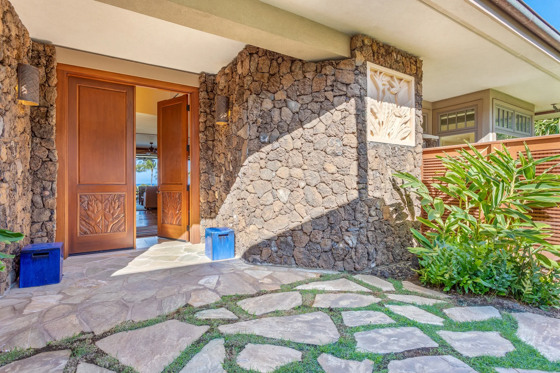 Una entrada de piedra con puertas de madera abiertas y un sendero de losas.