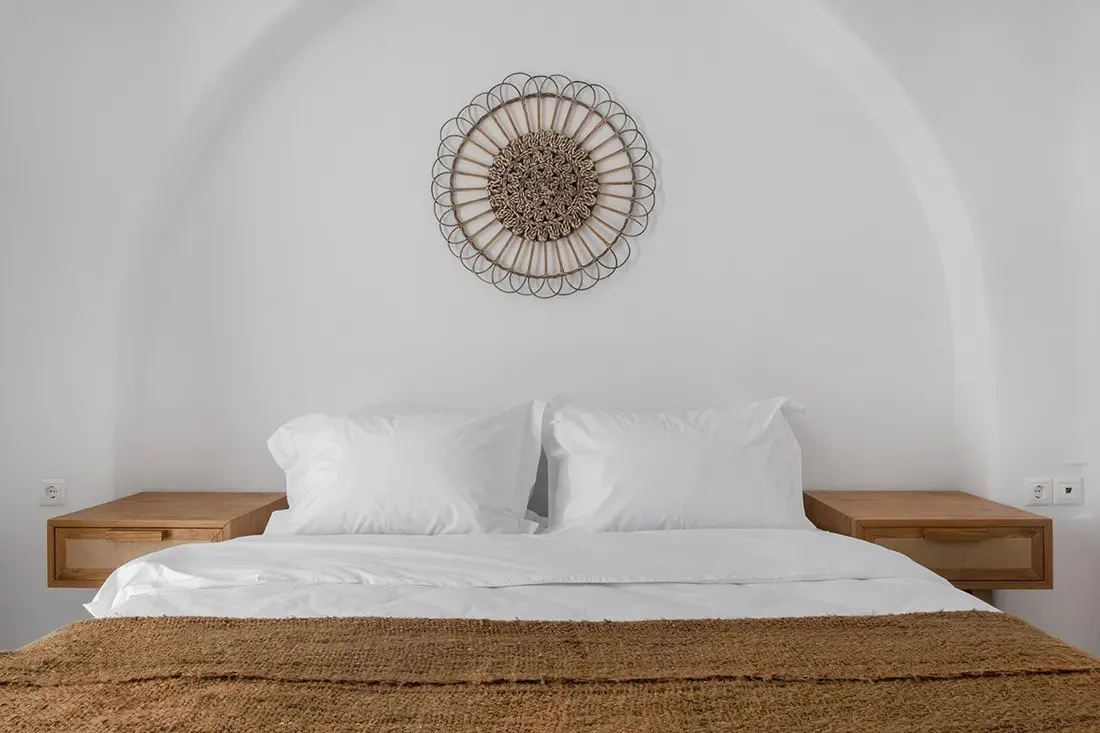 Un dormitorio con una cama bien tendida y una decoración circular tejida en la pared.