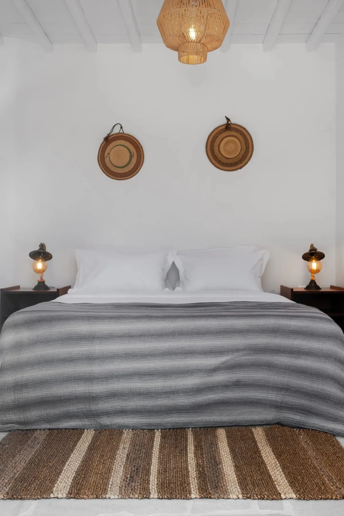 Un dormitorio con una cama bien hecha y dos adornos tejidos en la pared.