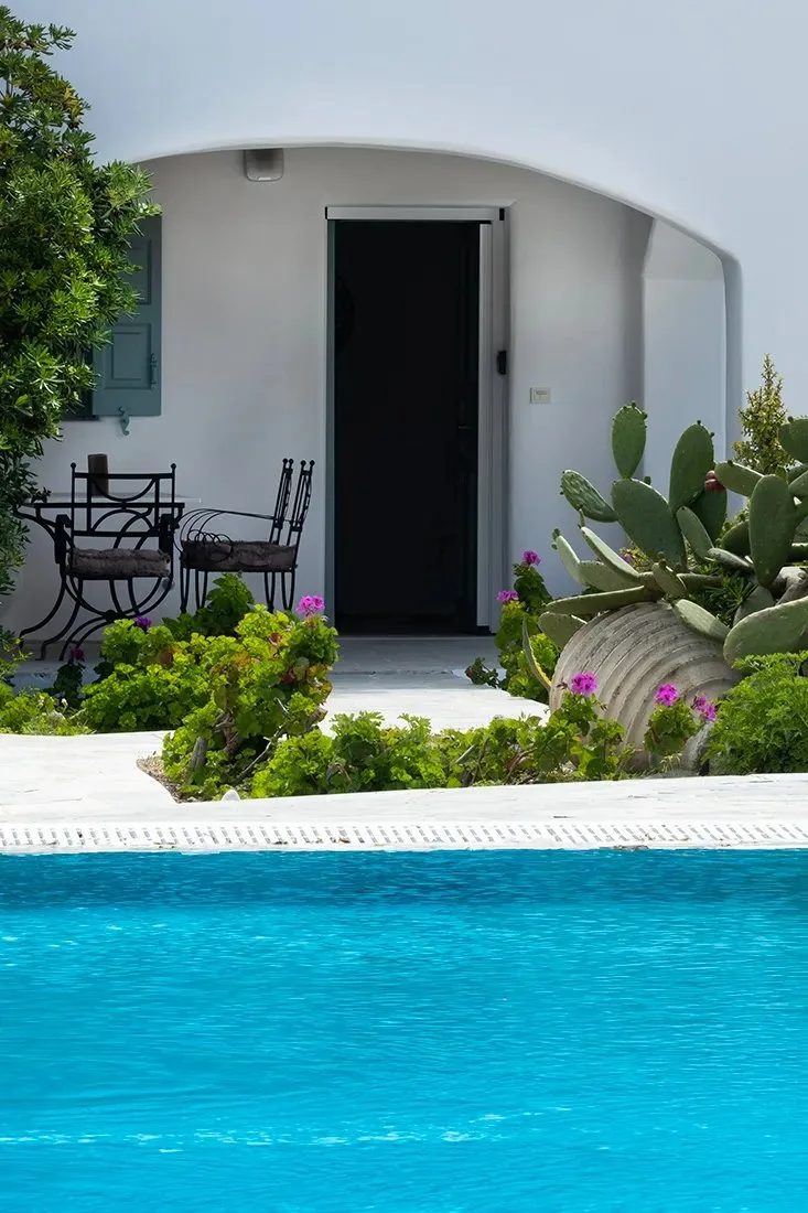Zona común: Una piscina junto a un edificio blanco con un patio sombreado.