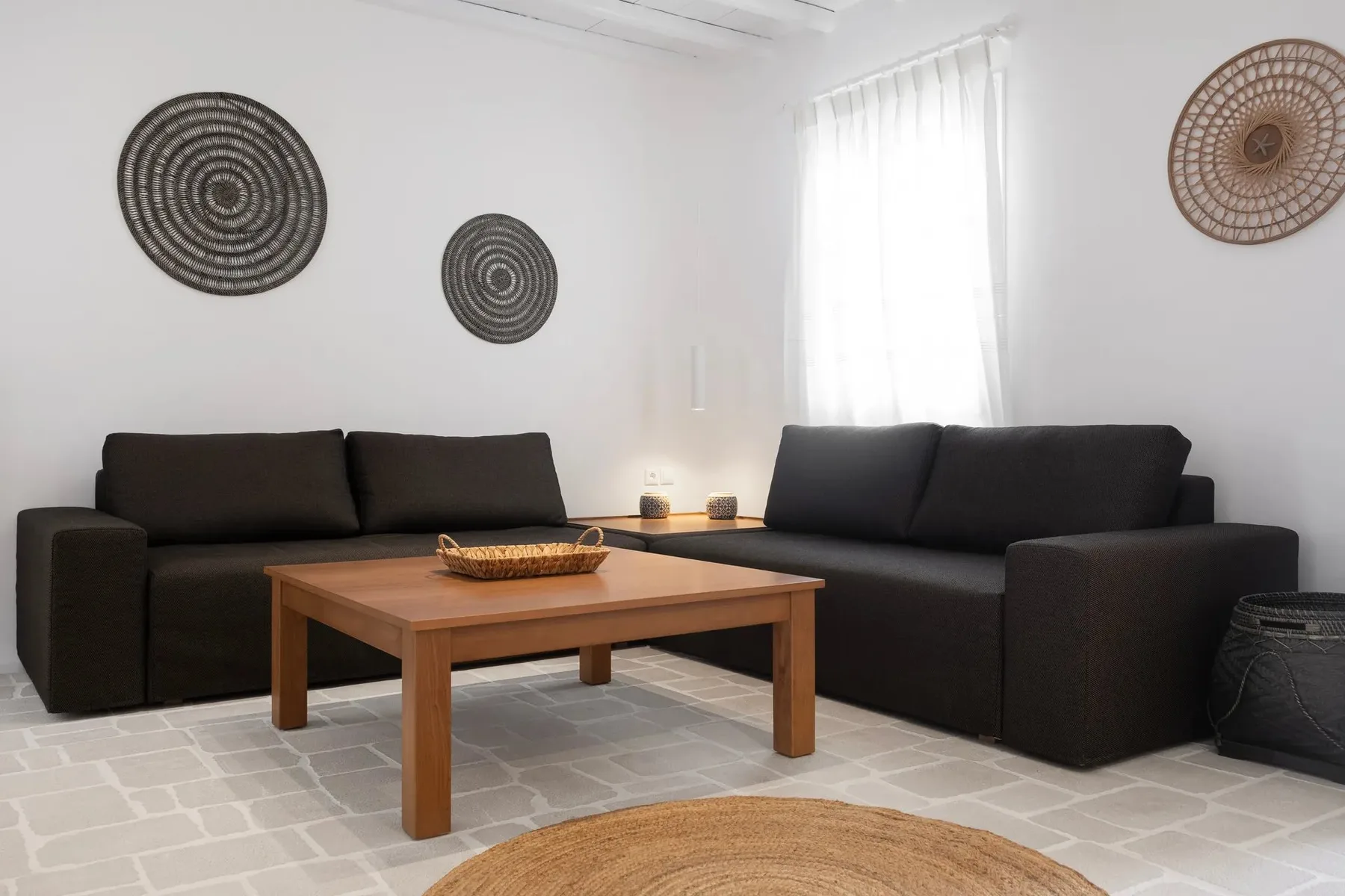 Una sala luminosa tiene asientos oscuros alrededor de una mesa de centro de madera.