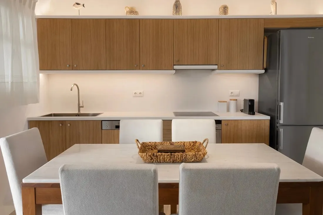 Comedor junto a una cocina moderna, con una mesa y asientos tapizados.