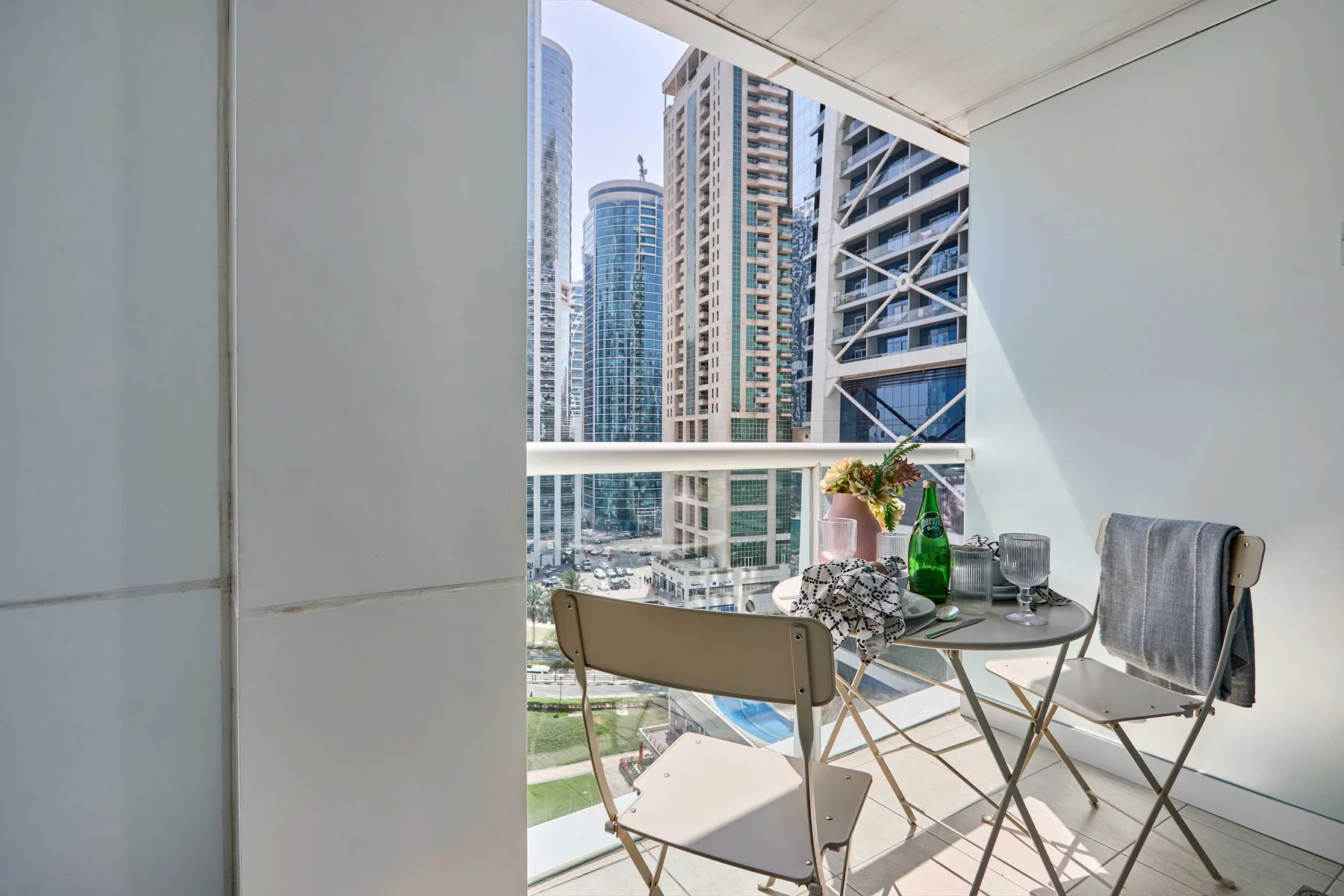 A balcony seating area with a small table overlooks modern high-rise buildings.