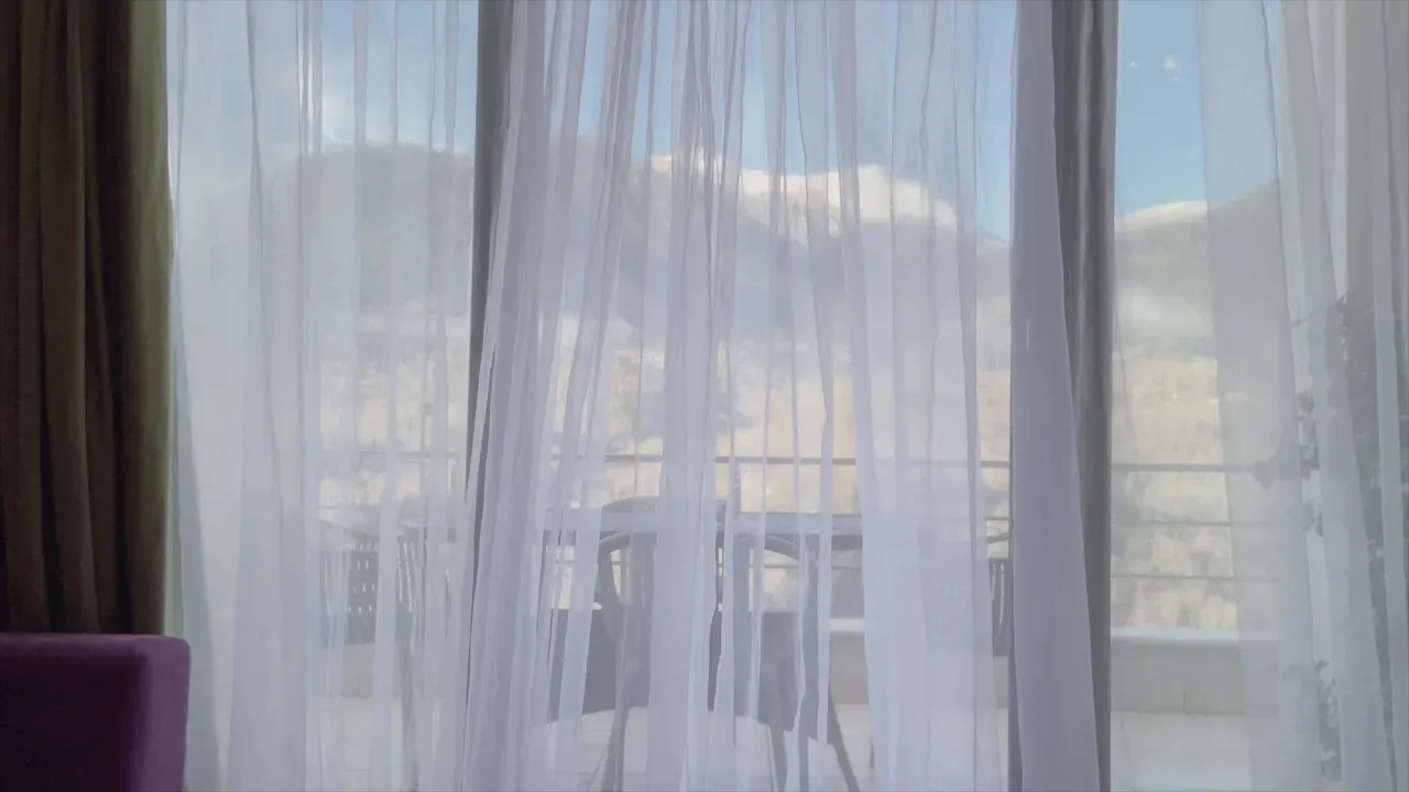 Espacio representativo del hotel: Una habitación luminosa con cortinas translúcidas que dan a un balcón.