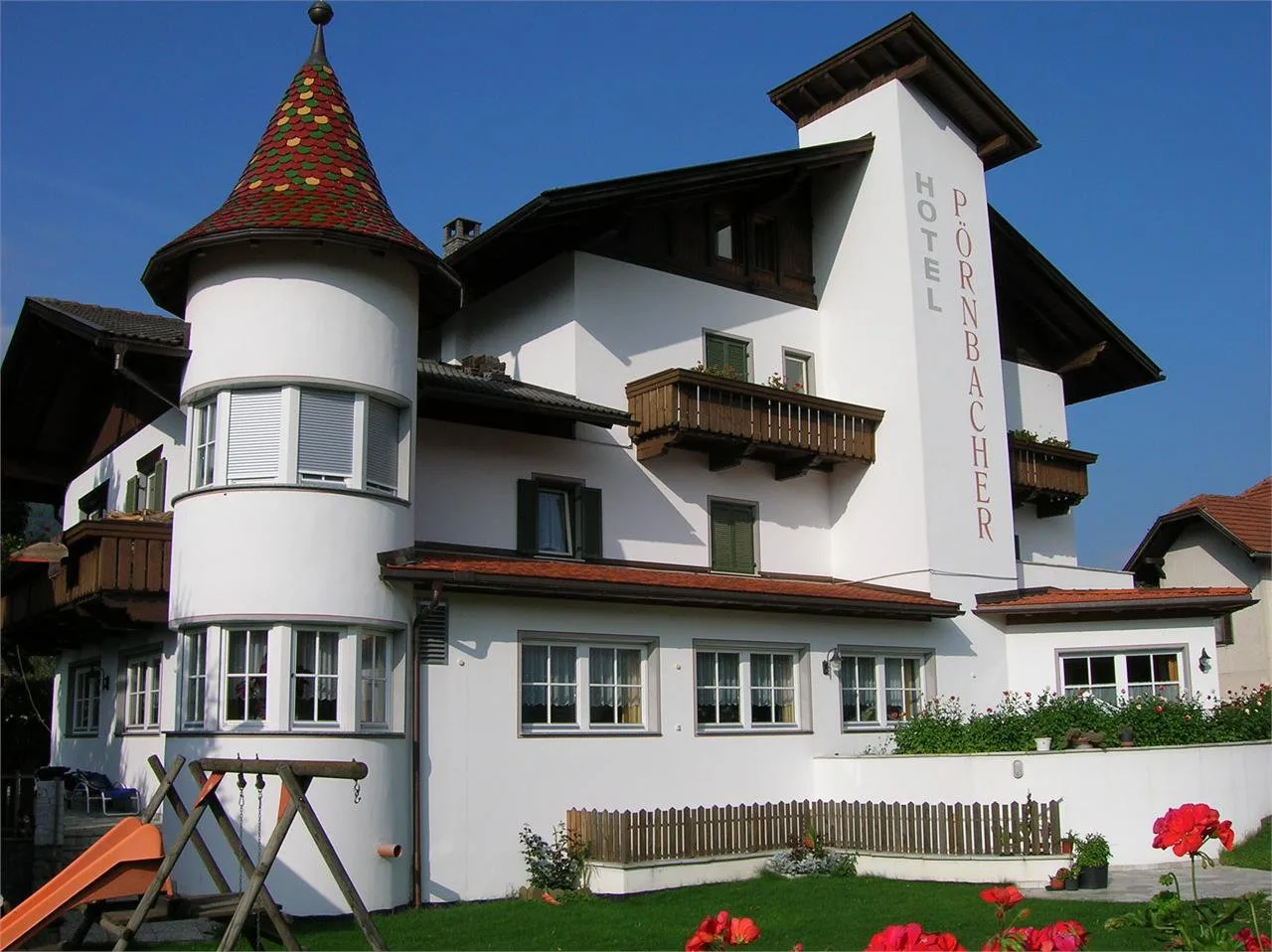 Representative hotel space: A white hotel building with balconies, a turret, and a landscaped garden.