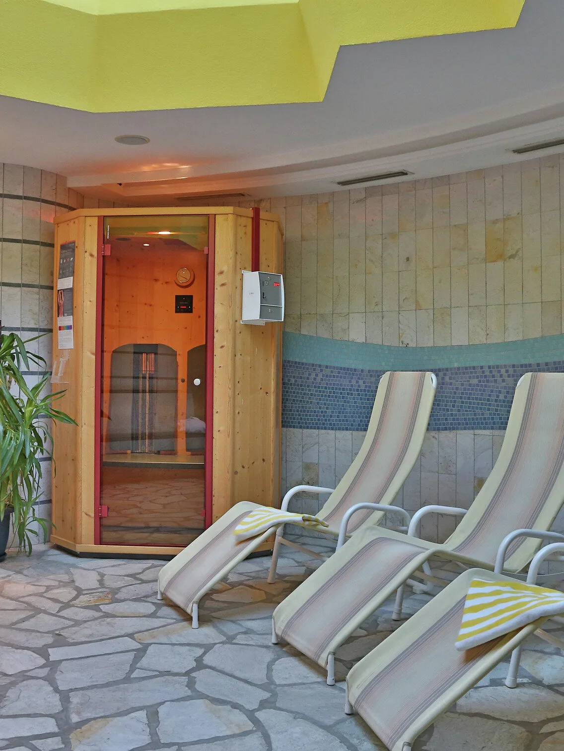 Representative hotel space: A spa relaxation area with reclining loungers beside a wooden sauna.