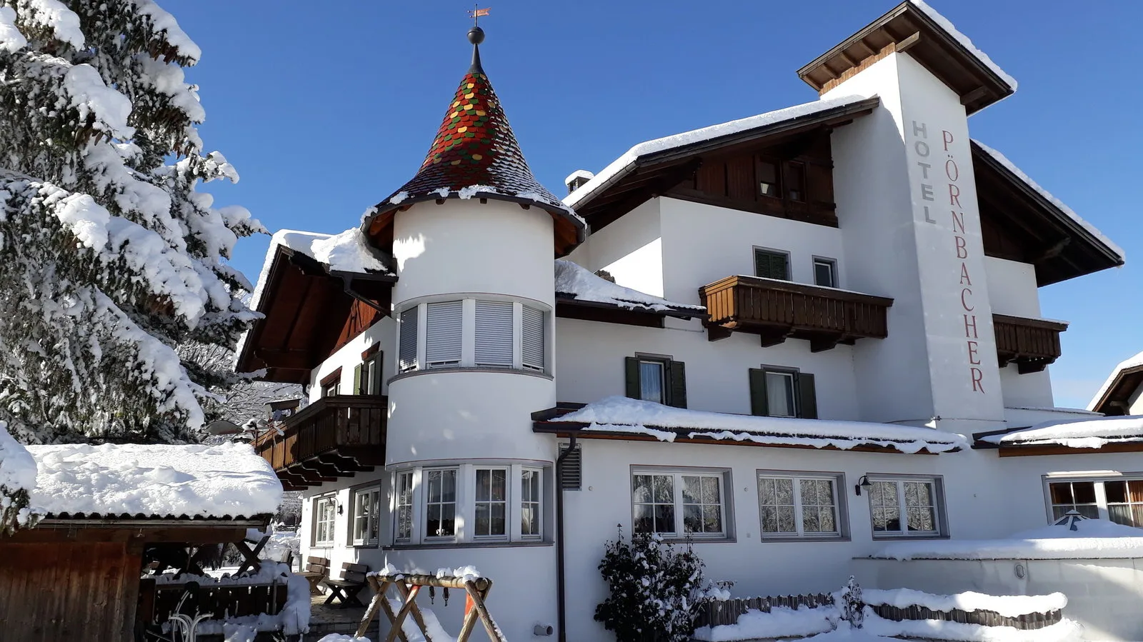 Representative hotel space: A snow-covered hotel building with balconies and a decorated turret stands beneath a clear sky.