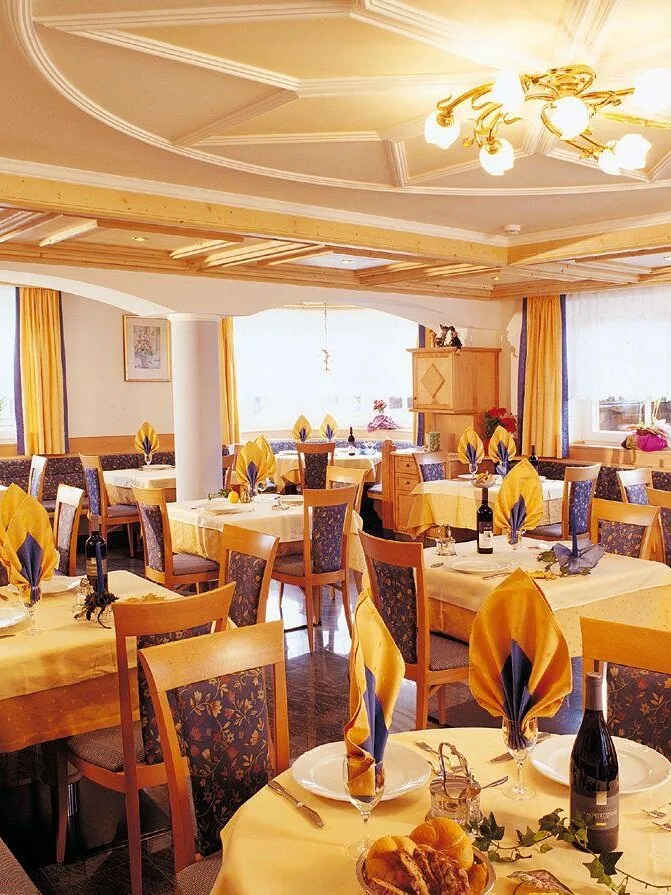 Representative hotel space: A dining room with tables set with folded napkins and place settings.