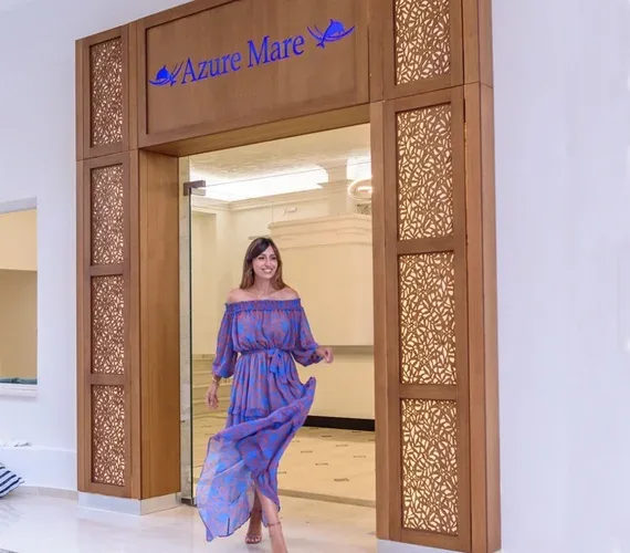 Representative hotel space: A woman in a blue dress walks through an ornate wooden doorway.