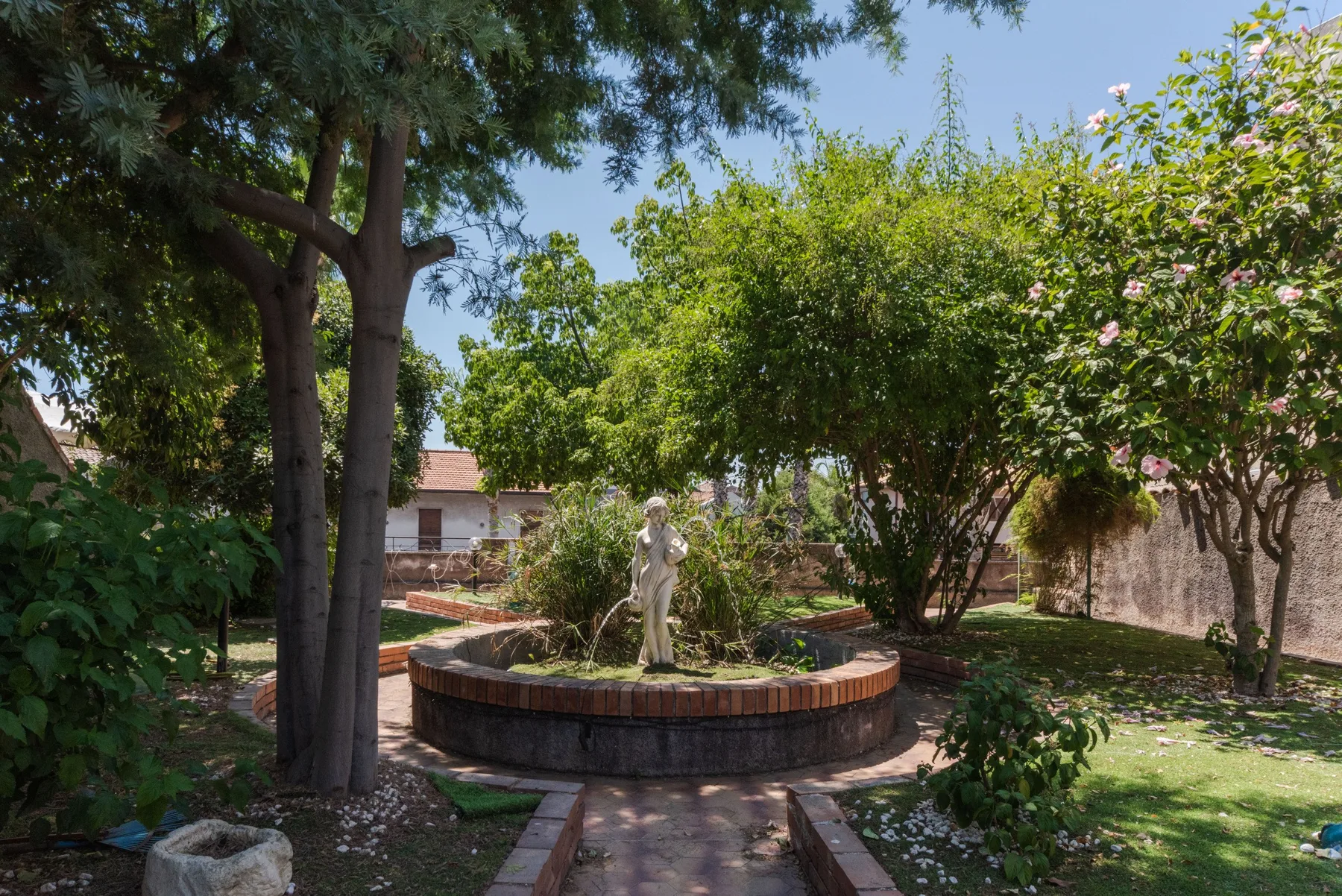 Zona común: Un jardín con una fuente central y árboles alrededor.