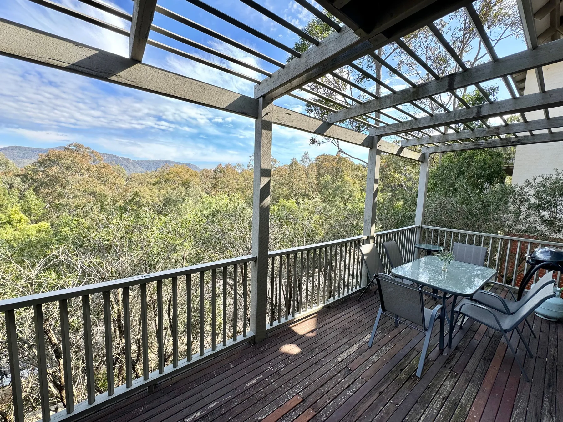 Una terraza cubierta con asientos al aire libre da a una ladera boscosa.