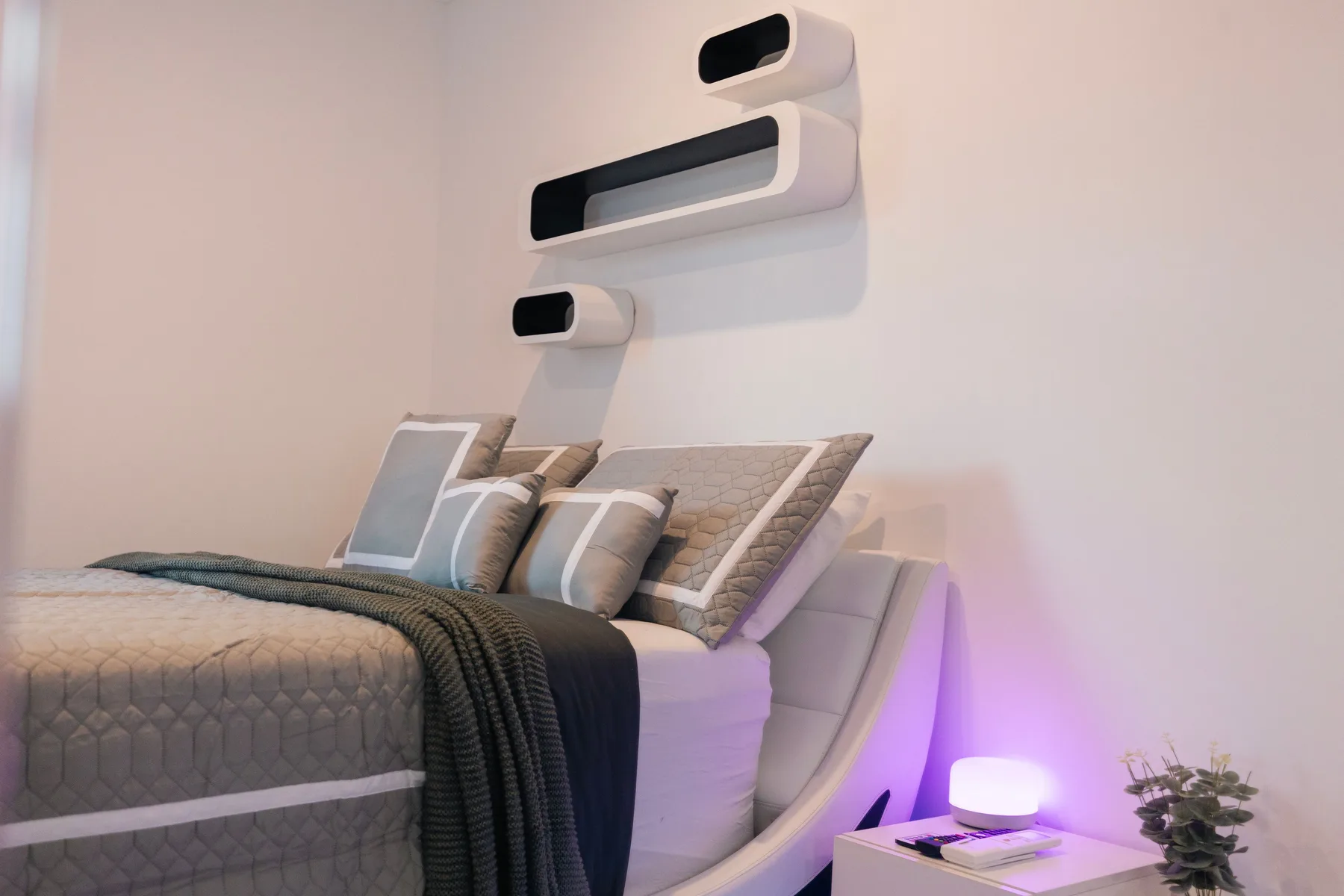 Un dormitorio con una cama bien arreglada y luminarias modernas en la pared.
