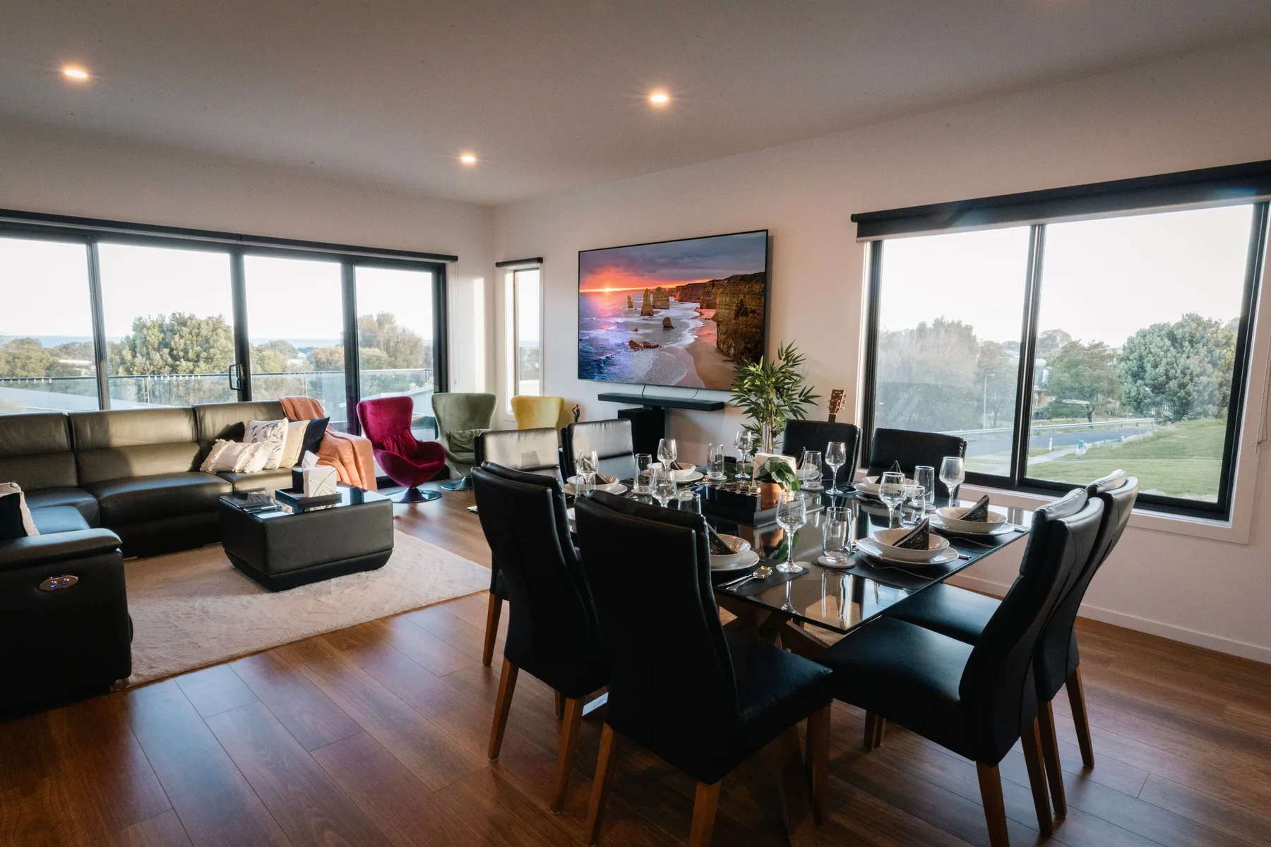 Comedor y sala de estar con una mesa puesta junto a grandes ventanales.