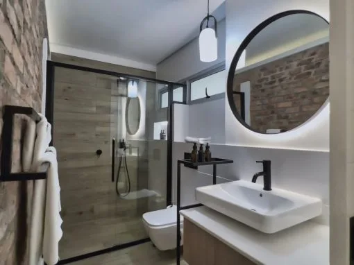 Espacio representativo del hotel: Un baño moderno con ducha de vidrio y lavabo blanco.